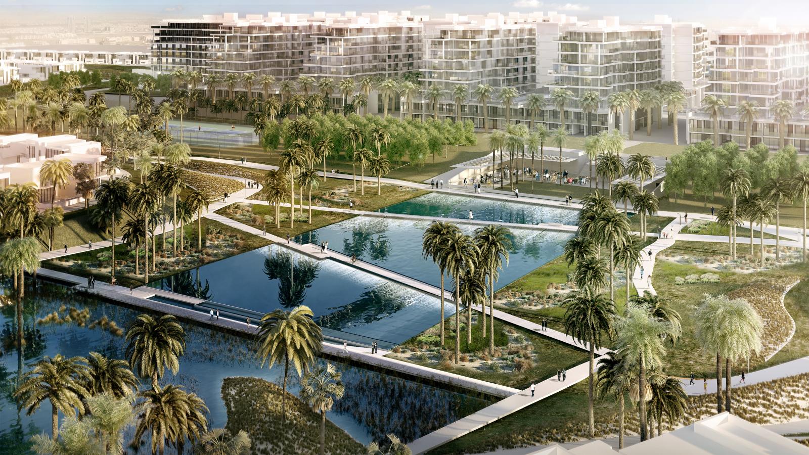 Akoya Park is a modern urban oasis featuring three large reflecting ponds surrounded by palm trees and grassy areas. Pathways meander through the park and connect to contemporary residential buildings in the background. People can be seen walking and biking on the paths.