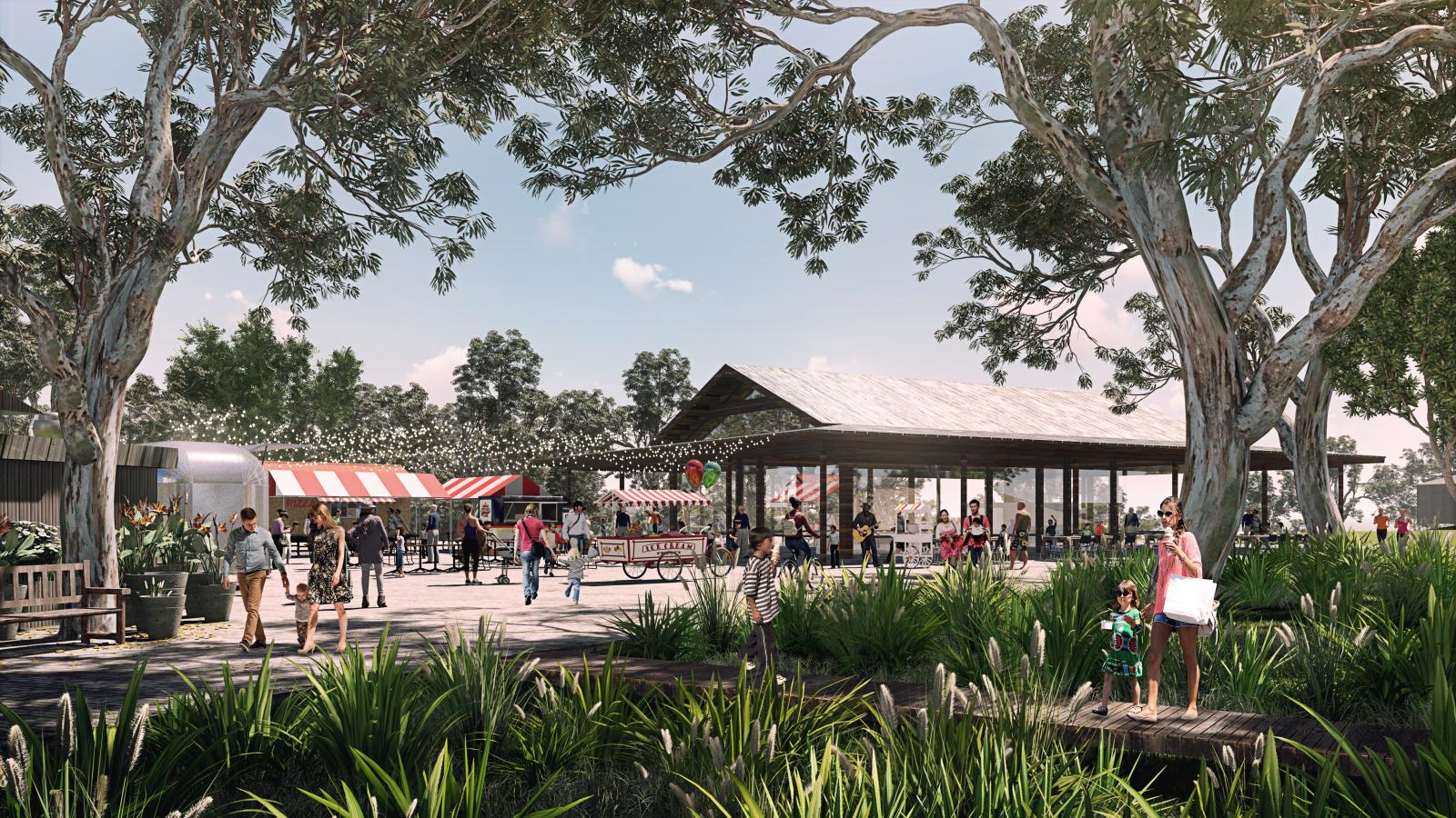 A lively outdoor market scene at the Castle Hill showground features various stalls and a food truck under a pavilion. People are walking, shopping, and socializing among trees and greenery. In the foreground, a person holds a child's hand near tall grasses and plants on this sunny day.