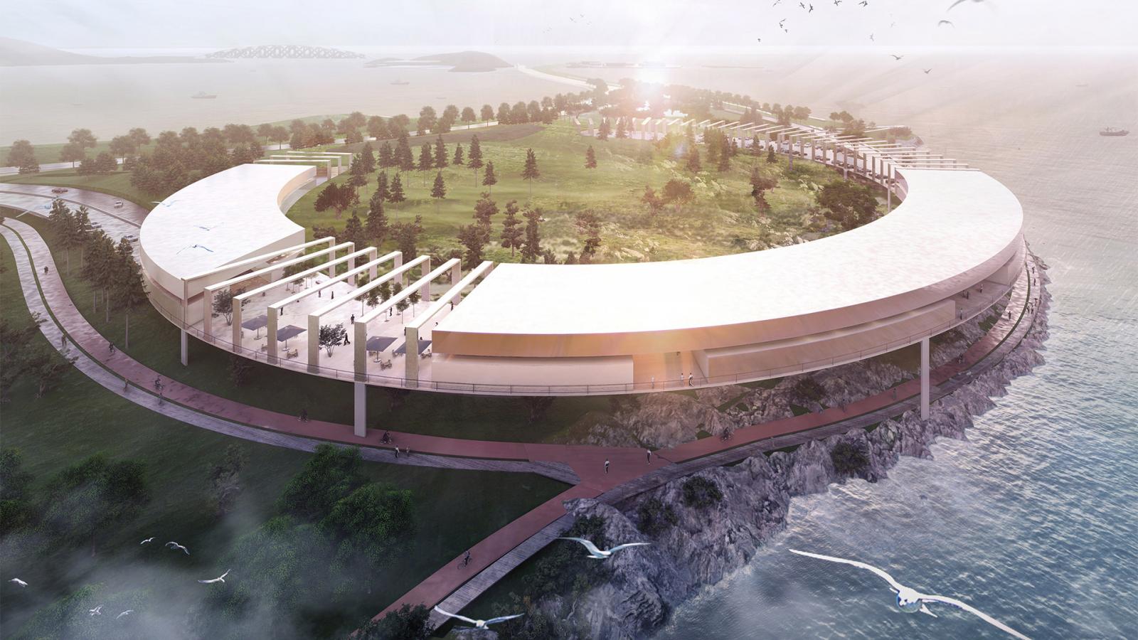 Aerial view of a large, circular structure with a partial roof, built on a seaside cliff on Daishan Island. The building has an open roof design on one side, revealing green space within. Surrounding walkways follow the shape of the structure and sea birds are flying around the area.