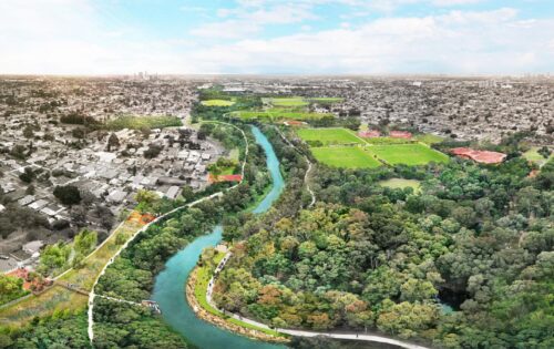 A vibrant aerial view of a city landscape with the Duck River winding through the middle. The left side displays urban buildings and homes, while the right side features lush greenery, parks, and sports fields. This masterplan highlights harmony between urban development and natural beauty under a partly cloudy sky.