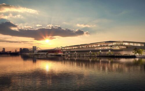 A serene waterfront view at sunset, with a modern building featuring large windows and terraces extending over the water. The sky is adorned with clouds and a golden hue from the setting sun reflecting on the calm water surface, reminiscent of the picturesque surroundings near Excel London.