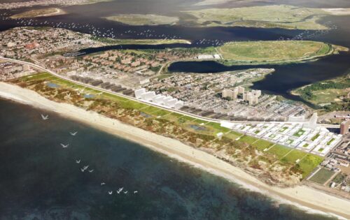 Aerial view of the Far Rockaways coastal urban area featuring beachfront, residential and commercial buildings, and greenery. Birds are flying over the water, and there are small islands and recreational areas visible in the background.