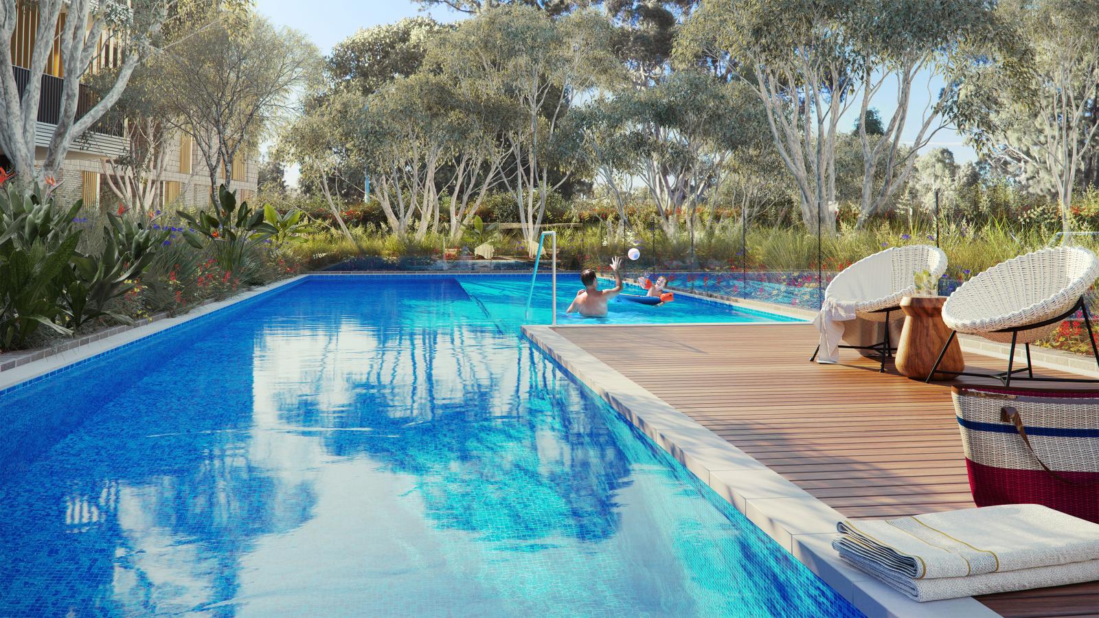 A serene outdoor pool in the heart of Leichhardt, surrounded by lush greenery and trees. Two lounge chairs and a table with a basket are on the wooden deck. People are enjoying the pool; one person is floating on a chair and another is holding a beach ball. Towels are neatly folded nearby.