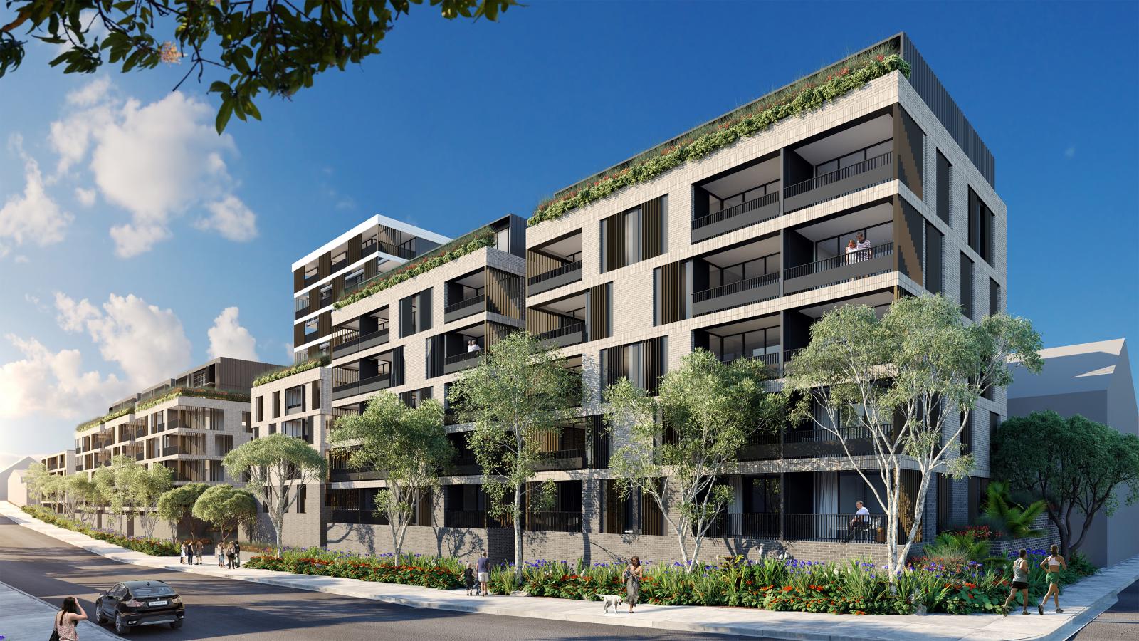 A modern green apartment complex with multiple stories under a clear blue Leichhardt sky. The buildings feature large glass balconies and have greenery on the rooftop and surrounding areas. Trees and shrubs line the sidewalk, and a few people are walking and cycling.