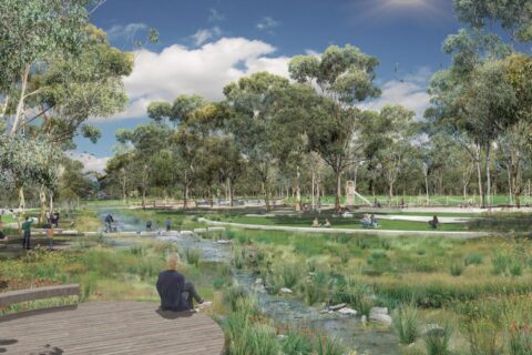 Lewis Park, a serene scene with green open spaces and trees, comes alive with people walking, biking, and sitting near a flowing stream crossed by small bridges. A clear blue sky overhead enhances the peaceful atmosphere of this beautifully designed masterplan.