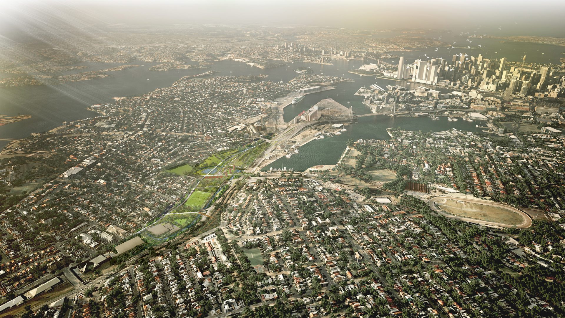 Aerial view of a densely populated urban area with numerous buildings, roads, and green spaces. A large body of water lies next to a prominent skyline with high-rise structures in the distance. Sunlight illuminates the scene from the top left, highlighting the city's intricate transport infrastructure.