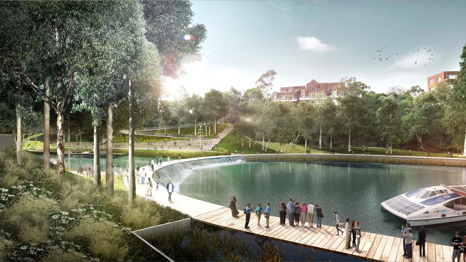 A scenic waterfront park with a curved boardwalk along a calm river, where people are gathered, enjoying the view. Tall trees and lush greenery surround the area. A boat is docked near the boardwalk, and buildings are visible in the background under Parramatta's clear sky as part of the City River Plan.