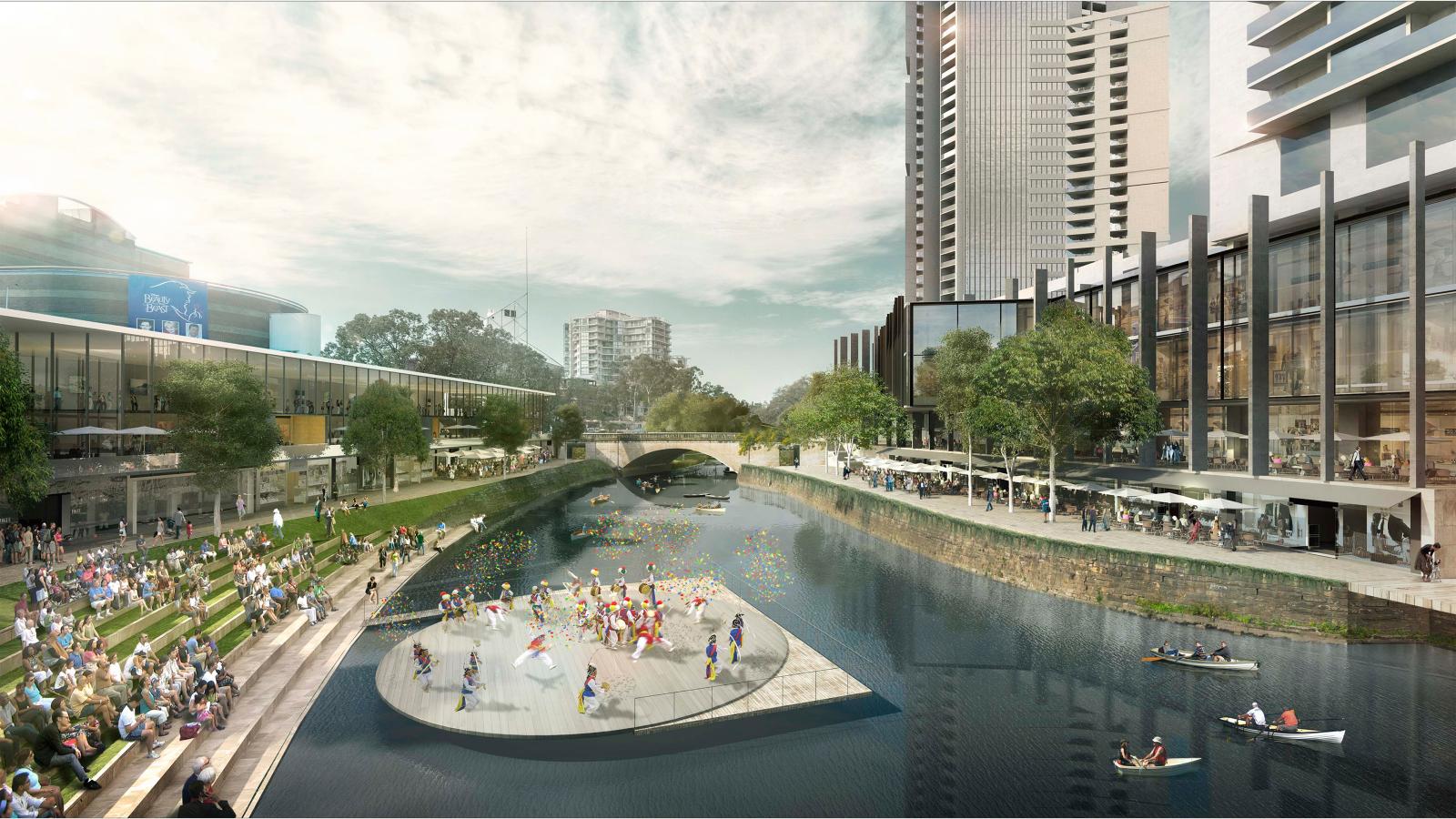 A vibrant riverfront city scene in Parramatta with people sitting on stepped seating along the grassy riverbank, watching performers on a circular floating platform. Tall modern buildings and a bridge are in the background. Small boats with people are visible on the river as part of the River Plan.