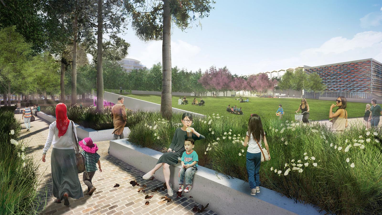 A vibrant scene at Paul Keating Park features people relaxing on benches and strolling along pathways. A woman with a child on her lap sits on a bench, while another child stands nearby. Groups of people are scattered on the grass, enjoying the sunny day, surrounded by lush greenery.