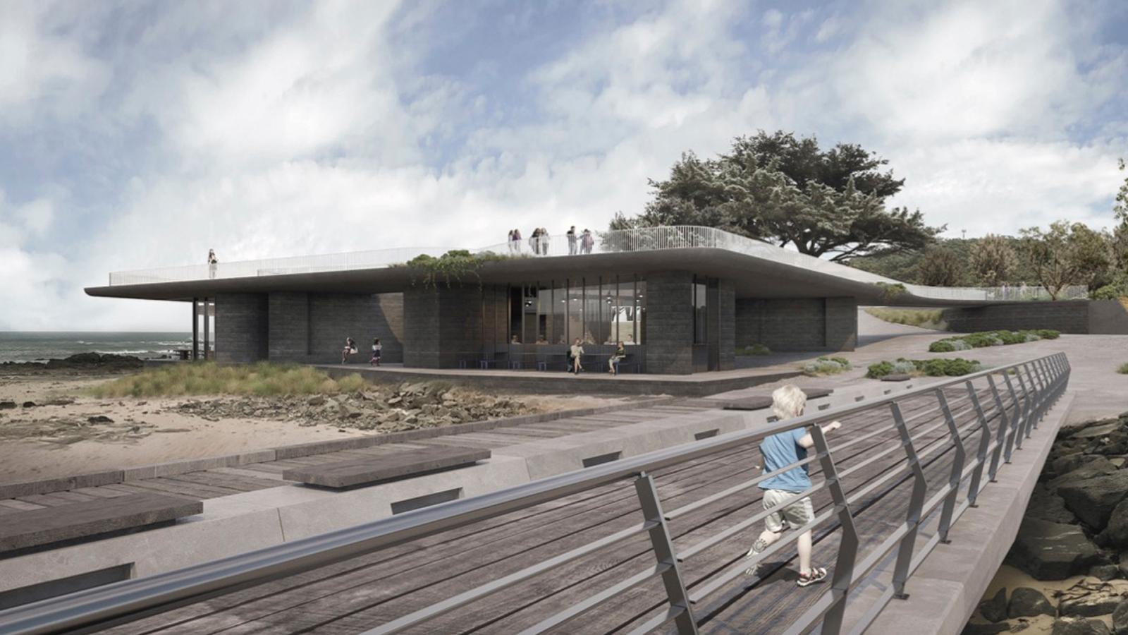 A modern, low-profile building with expansive glass windows and a sloped roof sits near the Point Grey coastline. People are walking along an adjacent boardwalk with railings. The sky is overcast, and nearby trees add to the natural scenery.