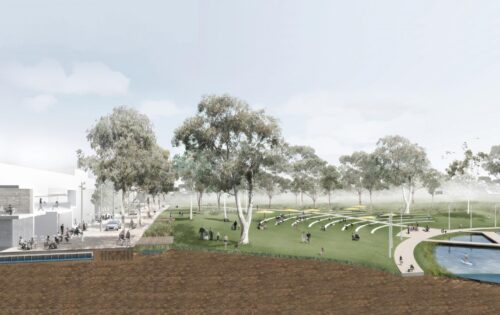 Image of a park in downtown Queanbeyan with a modern building on the left, surrounded by trees. In the center, people are sitting on tiered grass steps and benches. On the right, a water body with individuals walking on pathways adds to the serene atmosphere, inviting for outdoor activities.