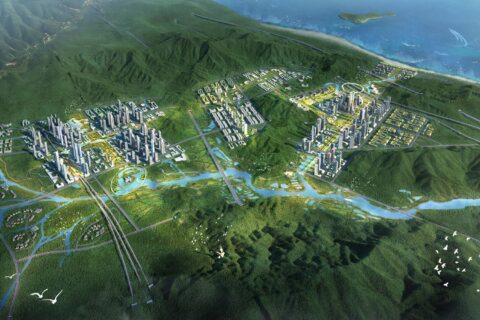 A detailed aerial view of Shenshan BioCity, an extensive, futuristic biohub integrated with lush greenery. Skyscrapers and residential buildings are dispersed among verdant hills, connected by roads, bridges, and waterways. The city is bordered by mountains and a body of water.