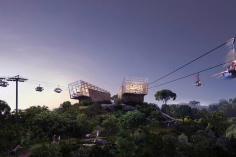 A scenic view at dusk shows the lush, green forest of Danaoke Mountain. A modern zipline runs across the sky, with individuals suspended and gliding through the air. In the background, two contemporary glass buildings grace a hill in Shenzhen, alongside a gondola lift line with people riding.