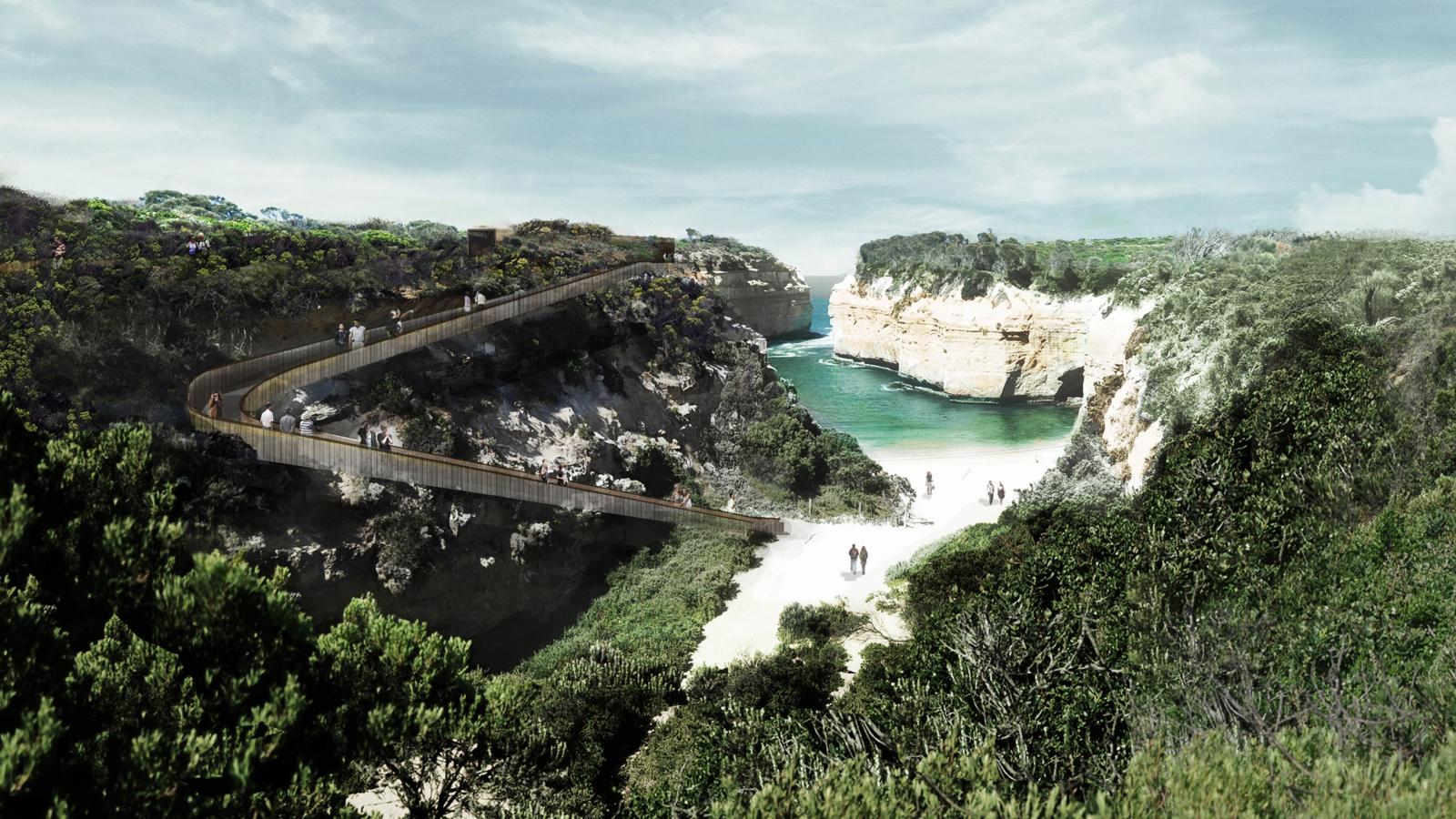 A scenic view of the Shipwreck Coast features a winding wooden bridge spanning across a lush, green gorge. The bridge overlooks a narrow, calm inlet with turquoise water, flanked by white limestone cliffs covered in vegetation. Visitors admire the picturesque surroundings.