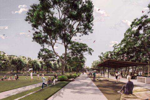 A spacious park scene with people enjoying various activities. On the left, individuals are sitting on grass and flying kites. The right features paved walkways, trees, and a covered area with benches. The sky is partly cloudy, and the atmosphere is serene and lively at Whittlesea Gardens.