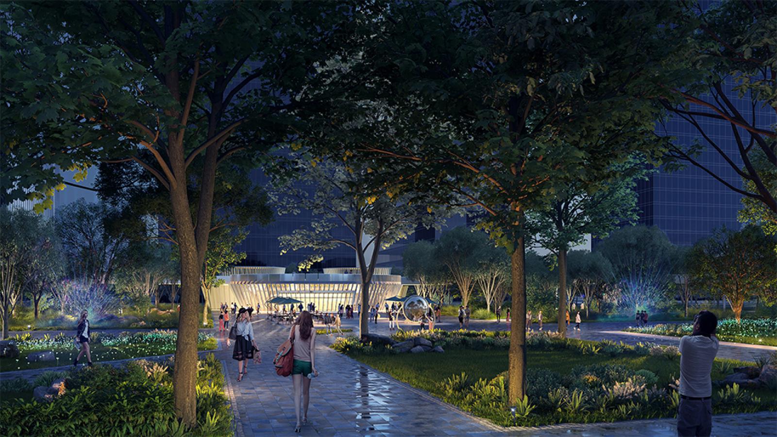 A nighttime park scene in Wuxi with people walking along a paved pathway surrounded by trees and greenery. The park is well-lit with streetlights, and the brightly lit Taihu Plaza building is visible in the background. The atmosphere is bustling yet tranquil.