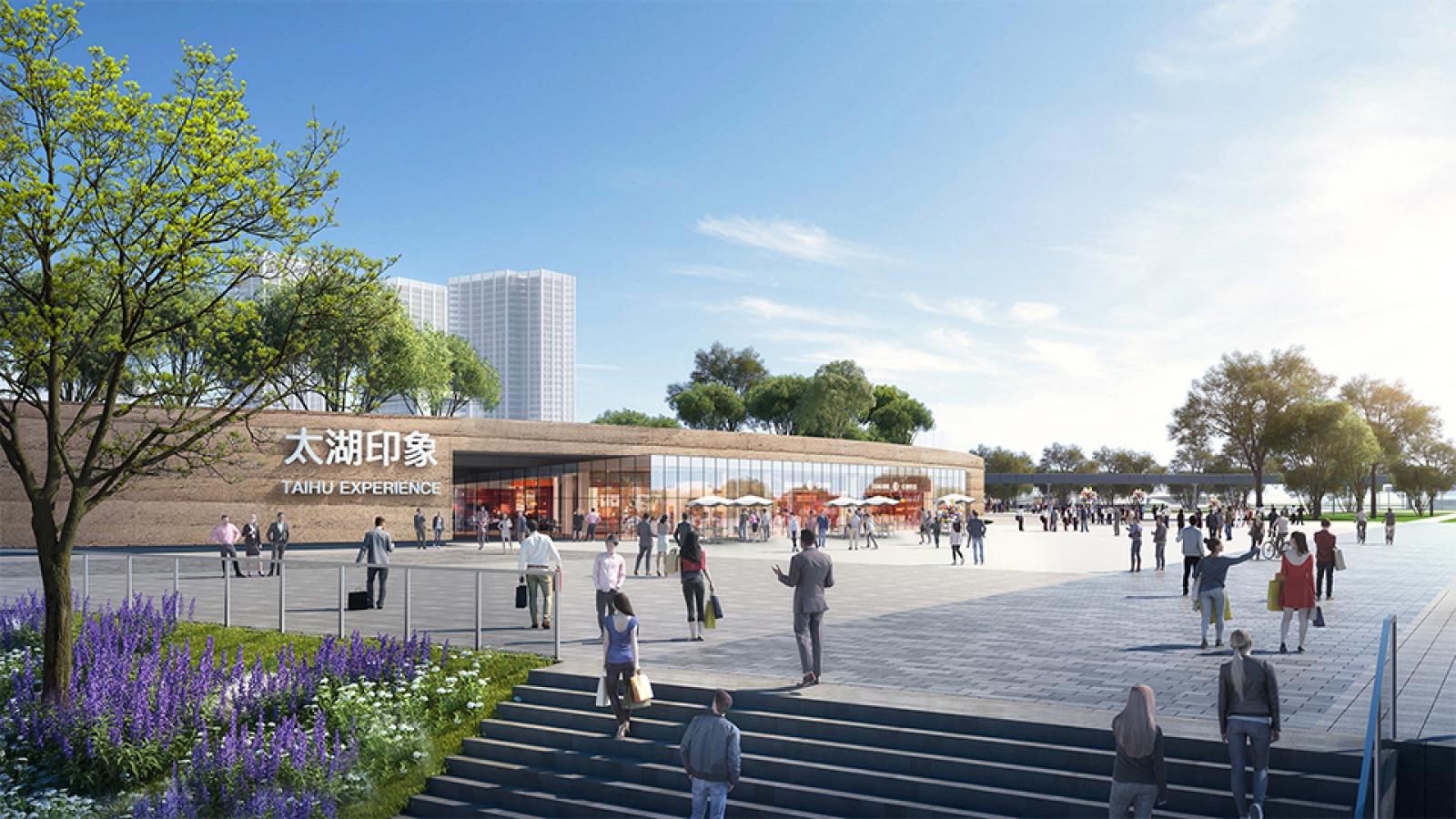 Image of a modern plaza with people walking and interacting. The plaza, known as Taihu Plaza in Wuxi, features a building with a large sign in both Chinese characters and English, reading "Taihu Experience." Trees and greenery surround the area under a clear, sunny sky.