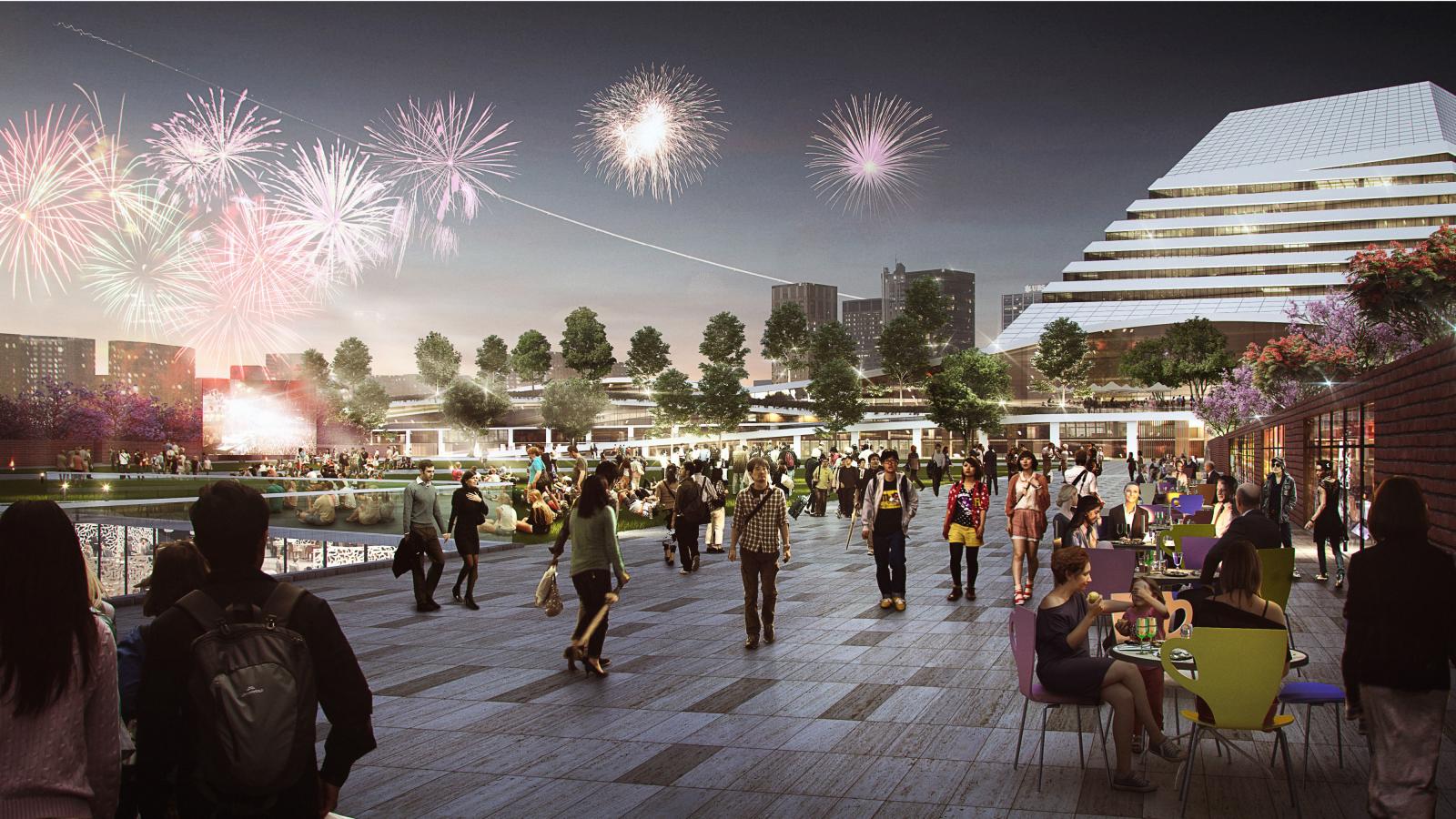 A lively evening scene with a crowd of people enjoying a waterfront event in Xiangmihu. Fireworks light up the sky, and modern buildings are visible in the background. Outdoor tables host groups socializing while others walk around, creating a festive atmosphere akin to Park City.