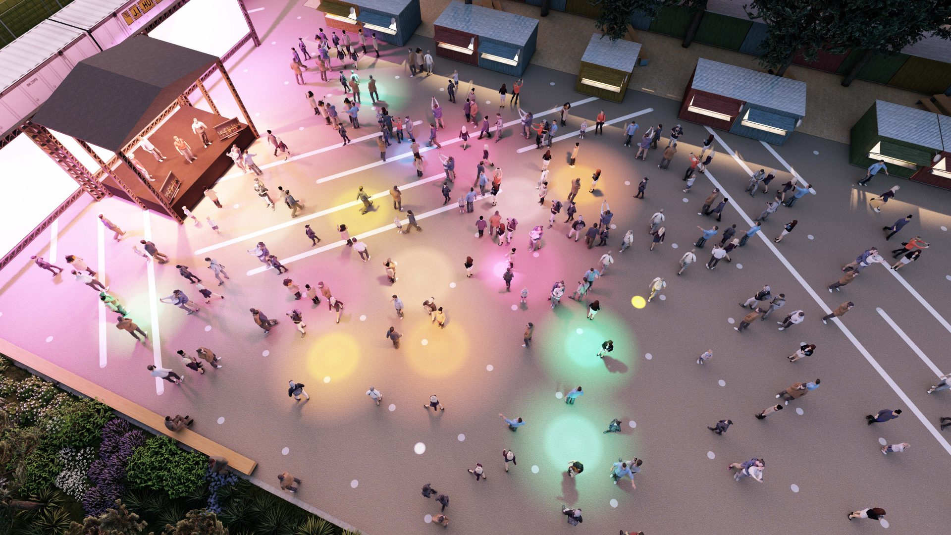 Aerial view of a colorful outdoor event at YTL Arena with a stage on the left featuring performers. The area is sprinkled with people standing and walking, illuminated by various multicolored lights creating a vibrant atmosphere. Several vendor stalls are visible in the background.