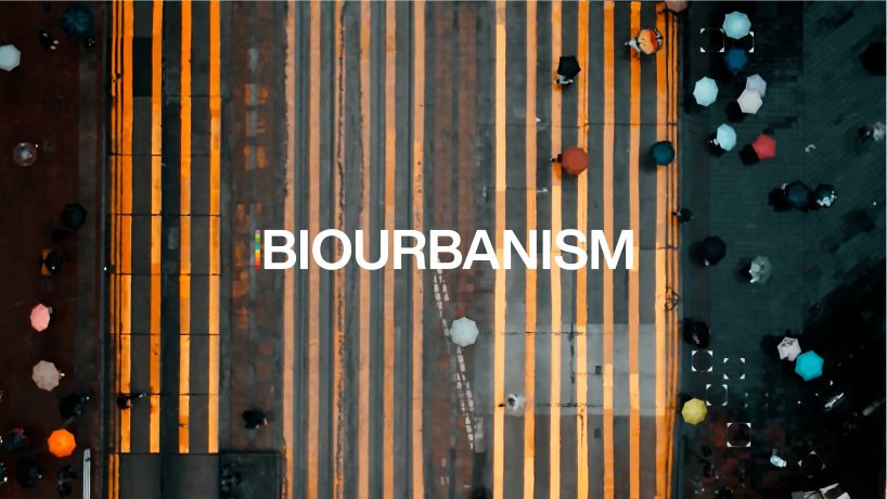 An aerial image of a crosswalk with yellow stripes features people holding colorful umbrellas as they navigate their daily careers. The word "BIOURBANISM" is prominently displayed across the image's center.