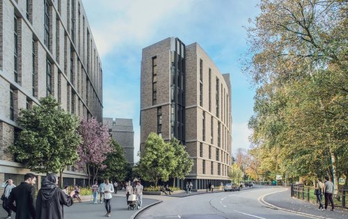 A modern residential building with a mix of light and dark brickwork stands along a curving street near Southampton. People walk on the sidewalk under leafy trees, with some benches and lampposts visible. The sky is clear with a few clouds.