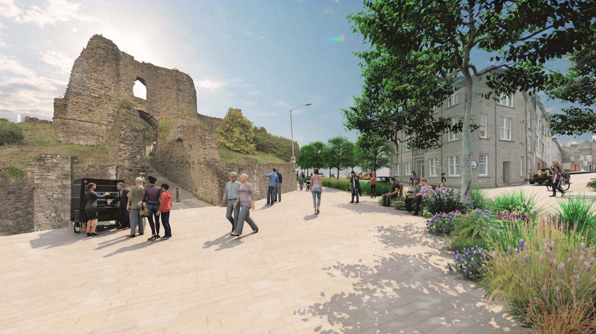 A lively outdoor area in Launceston with people walking and gathering near an ancient stone ruin. Trees and plants line a wide paved pathway, promoting Greener Streets. Some individuals are by a food stall, while others stroll along the path. Buildings and additional greenery are visible in the background.