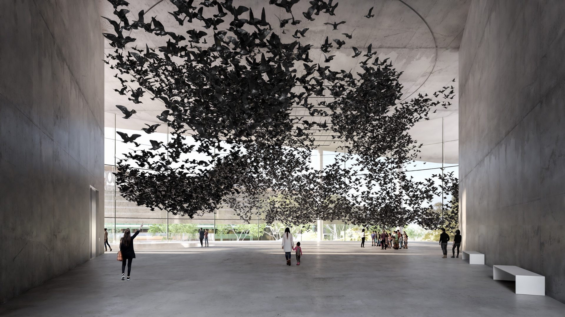 A spacious, modern gallery with concrete walls and high ceilings features a large art installation of numerous black birds suspended in mid-air. Visitors stand and walk around, admiring the exhibit. Natural light streams in from large windows at the National Gallery of Victoria, illuminating the space.