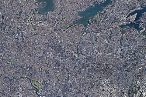 A detailed aerial view of the densely built urban area in the Inner West showcases a maze of streets and buildings. Green spaces, water bodies, and notable landmarks are scattered throughout, providing contrast to the clustered cityscape, reflecting the Blue-Green Grid Strategy.