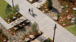 Aerial view of two people strolling through Henderson Park, a landscaped area flourishing with trees, shrubs, and rocks. The scene features garden beds and decorative stones, all part of the official opening celebrated by NINE by Mirvac.